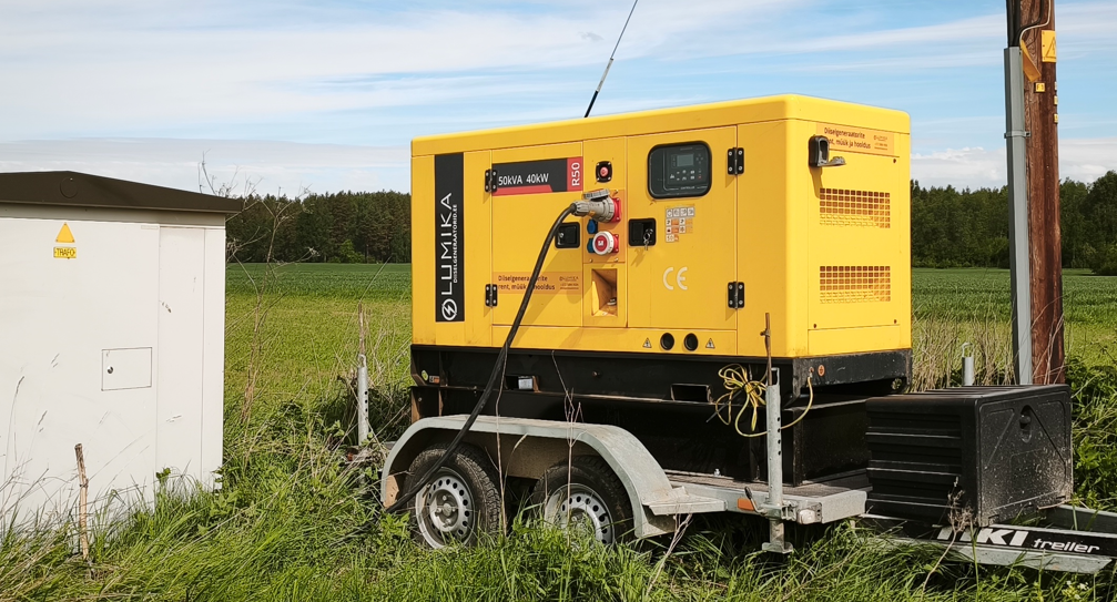 Kollane Lumika generaator haagisel elektrikilbi ja elektriposti kõrval.