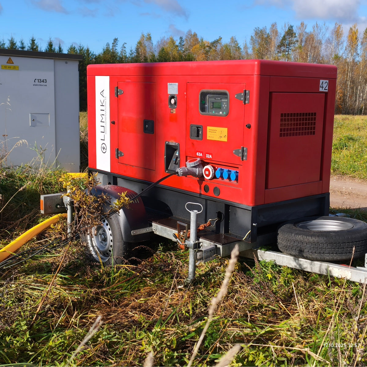 Punane Lumika generaator elektrikilbi kõrval, generaatori pistikutesse ühendatud kaablid.