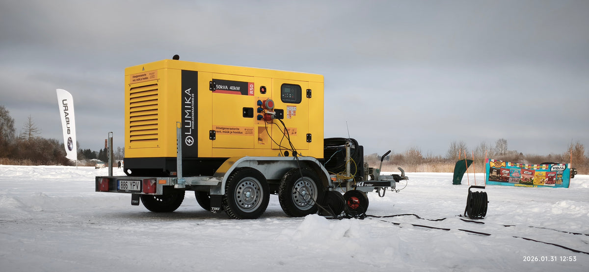 Kollane Lumika rendigeneraator haagisel lumisel platsil, generaatoriga ühendatud elektrikaablid.